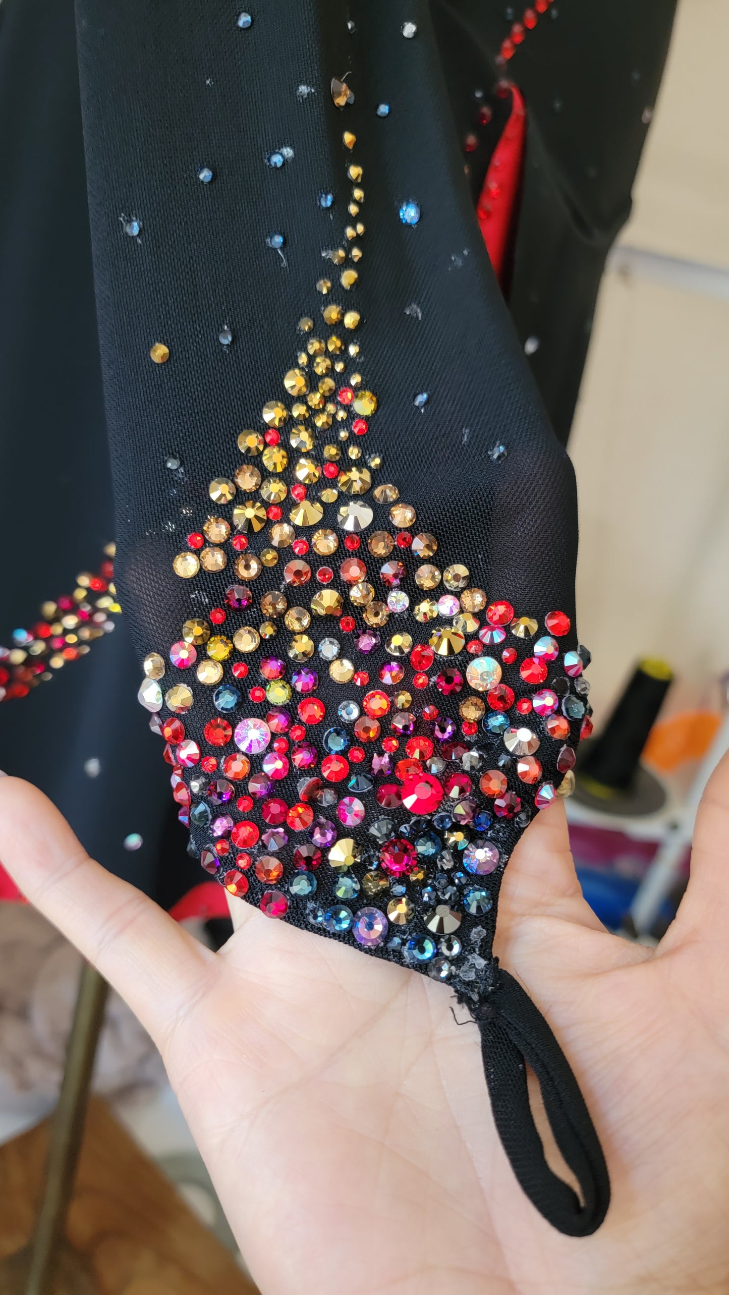Close-up of hand-applied multicolor rhinestone flame detail on black skating dress sleeve