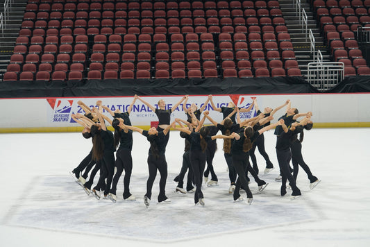 Synchronized skating team in matching black uniforms at US Figure Skating National Theatre on Ice Wichita